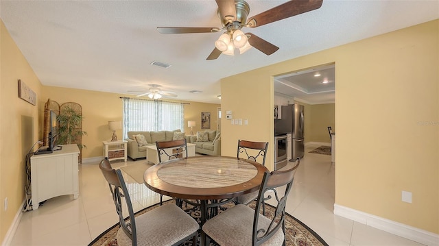 dining space with light tile patterned flooring, ceiling fan, visible vents, and baseboards