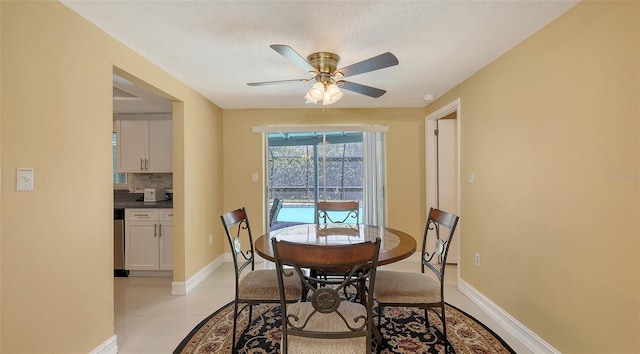 dining room featuring baseboards, a ceiling fan, a textured ceiling, light tile patterned flooring, and a sunroom