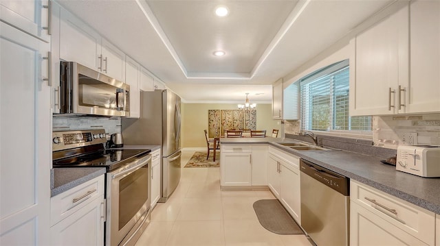 kitchen featuring a sink, stainless steel appliances, a notable chandelier, backsplash, and white cabinets