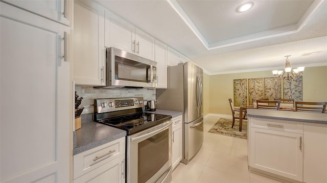 kitchen with stainless steel appliances, crown molding, decorative light fixtures, backsplash, and white cabinetry