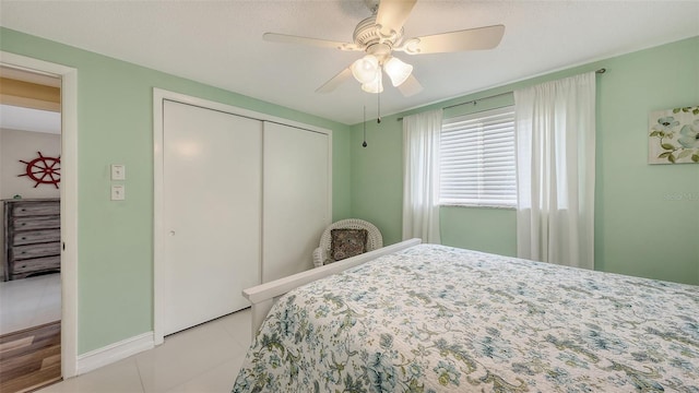 tiled bedroom with baseboards, a ceiling fan, and a closet