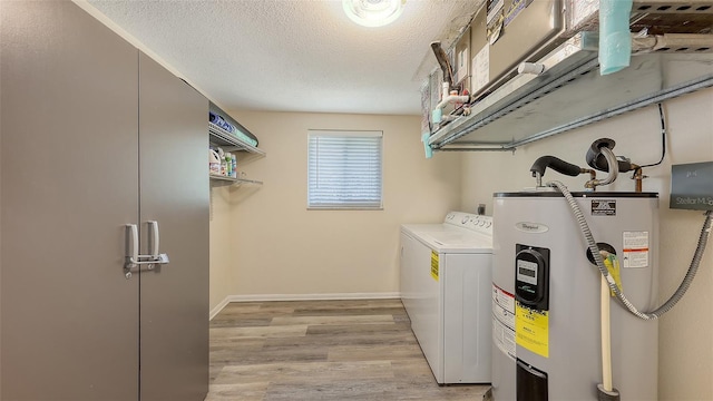 clothes washing area featuring washer and clothes dryer, laundry area, light wood-style flooring, a textured ceiling, and electric water heater