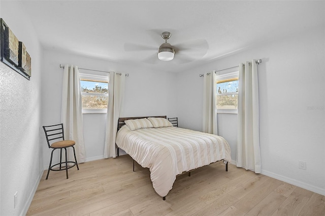 bedroom featuring a ceiling fan, baseboards, and light wood finished floors