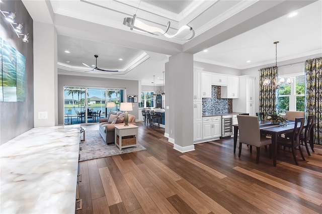 4625 Foxtail Dr, Parrish, FL 34219 - dining space featuring a tray ceiling, wine cooler, dark wood-type flooring, a chandelier, and ornamental molding