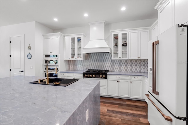 4308 Fly Rod Ter, Parrish, FL 34219 - kitchen featuring high end white fridge, dark wood-style floors, black cooktop, custom range hood, and white cabinetry