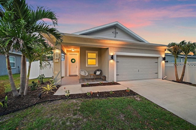 view of front of home with concrete driveway, stucco siding, a garage, fence, and covered porch