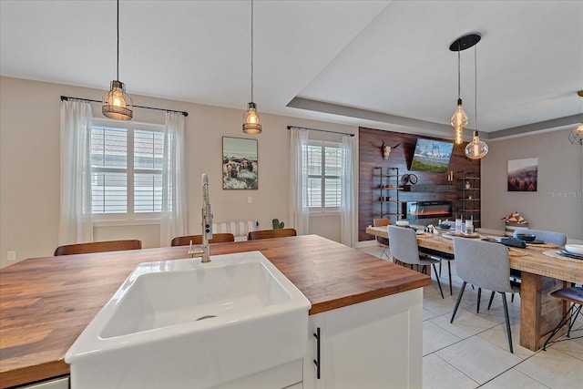 867 Bacon Ave, Sarasota, FL 34232 - kitchen with light tile patterned floors, pendant lighting, a sink, and wooden counters