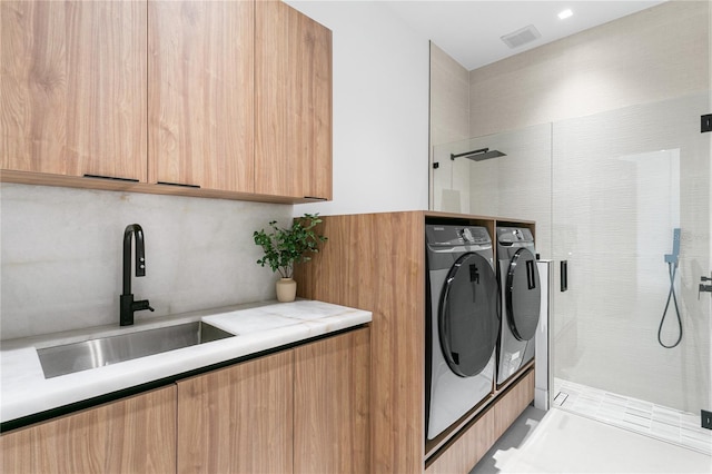 washroom with independent washer and dryer, a sink, cabinet space, and visible vents