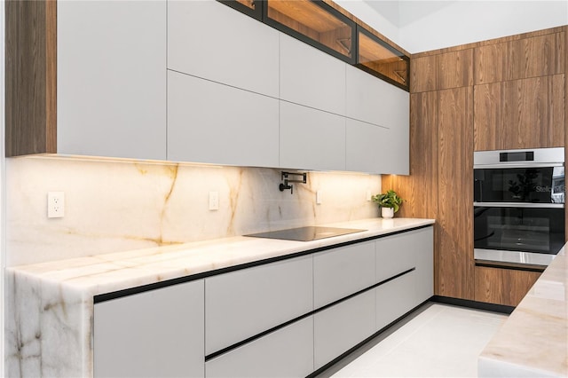 kitchen with stainless steel double oven, black electric stovetop, modern cabinets, white cabinets, and decorative backsplash