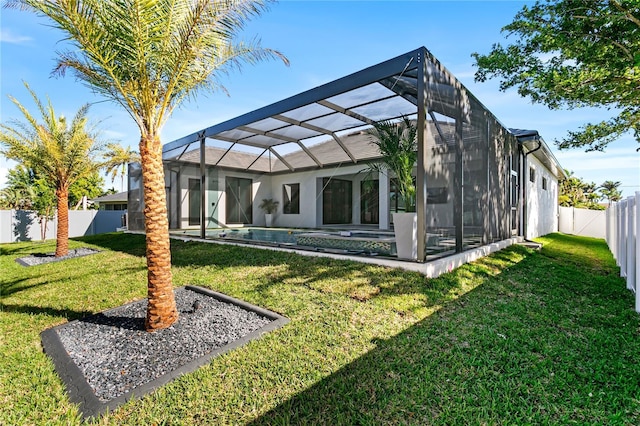rear view of property with a fenced backyard, stucco siding, glass enclosure, and a lawn