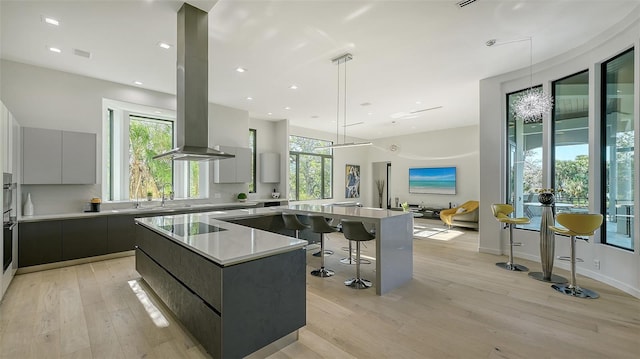1540 Hillview Dr, Sarasota, FL 34239 - kitchen with light countertops, modern cabinets, island range hood, a spacious island, and light wood-type flooring