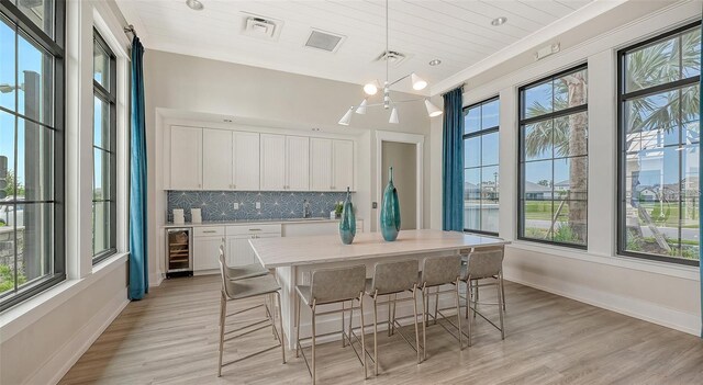 17502 Savory Mist Cir, Bradenton, FL 34211 - dining space with beverage cooler, light wood-type flooring, a chandelier, and baseboards