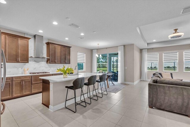17502 Savory Mist Cir, Bradenton, FL 34211 - kitchen with wall chimney range hood, open floor plan, tasteful backsplash, a center island with sink, and a kitchen breakfast bar