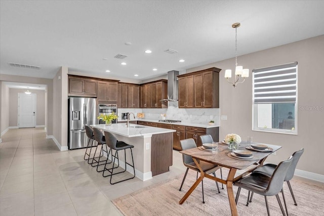 17502 Savory Mist Cir, Bradenton, FL 34211 - kitchen featuring stainless steel appliances, a sink, wall chimney range hood, decorative backsplash, and a chandelier