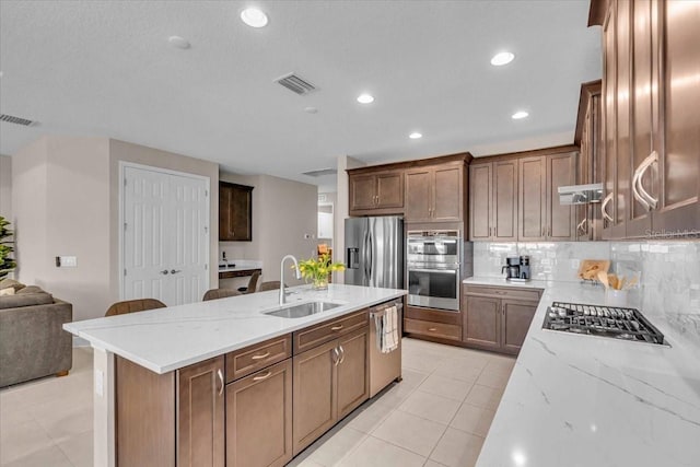 17502 Savory Mist Cir, Bradenton, FL 34211 - kitchen with a sink, stainless steel appliances, tasteful backsplash, a center island with sink, and light stone countertops