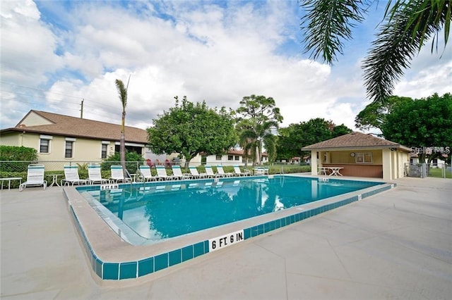 community pool with fence and a patio