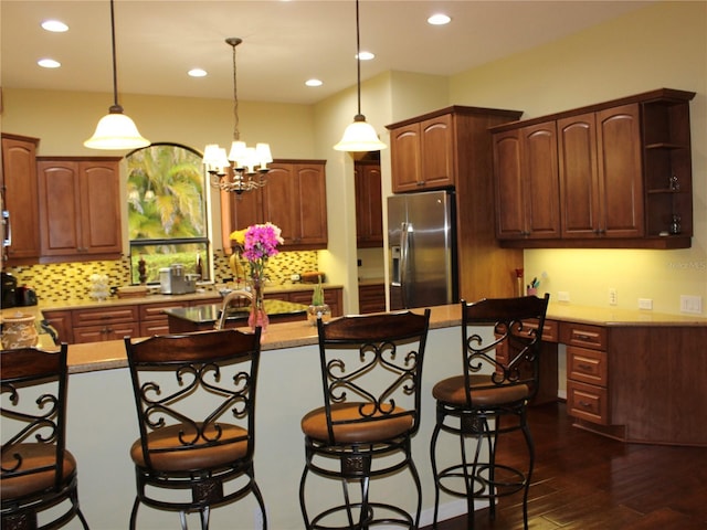 406 Petrel Trl, Bradenton, FL 34212 - kitchen with tasteful backsplash, a breakfast bar area, decorative light fixtures, stainless steel refrigerator with ice dispenser, and dark wood-type flooring