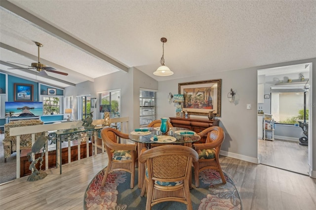 dining room featuring a textured ceiling, lofted ceiling, wood finished floors, and a ceiling fan