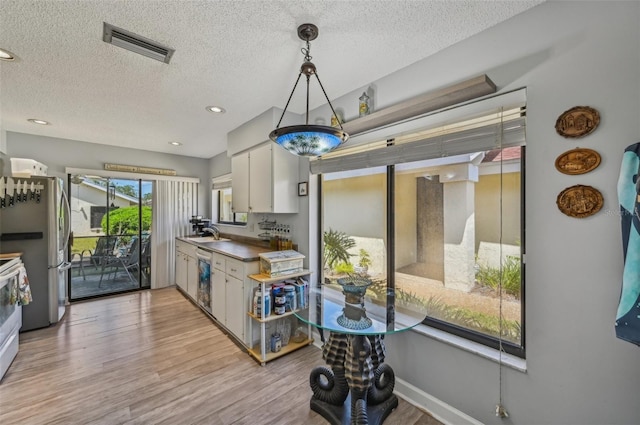 kitchen featuring visible vents, dishwasher, a sink, light wood-type flooring, and freestanding refrigerator