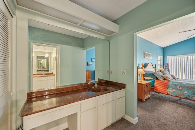 bathroom with vanity, vaulted ceiling, baseboards, a textured ceiling, and connected bathroom