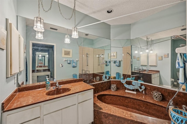 full bathroom featuring a textured ceiling, visible vents, two vanities, a sink, and a stall shower