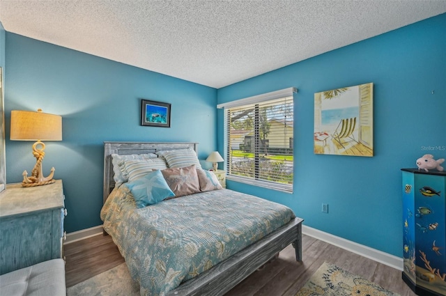 bedroom with baseboards, a textured ceiling, and wood finished floors
