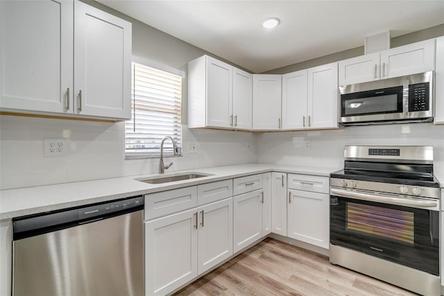 kitchen featuring stainless steel appliances, a sink, light countertops, and white cabinetry