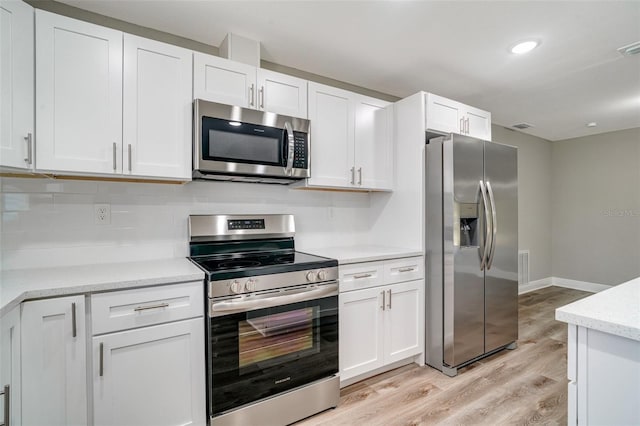 kitchen featuring stainless steel appliances, light wood-style flooring, white cabinets, backsplash, and baseboards