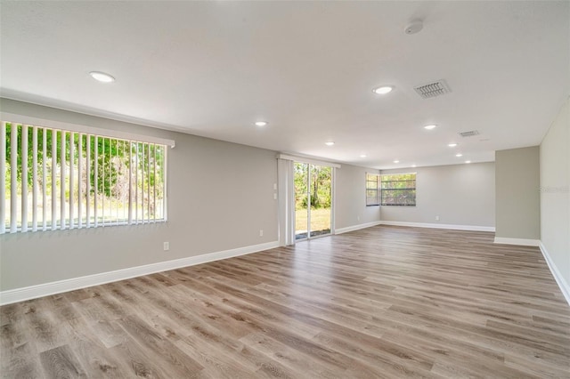 empty room featuring baseboards, recessed lighting, wood finished floors, and a smoke detector