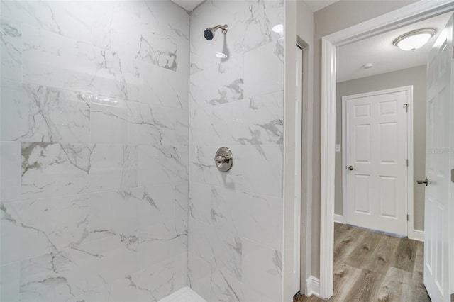 full bath featuring tiled shower and wood finished floors