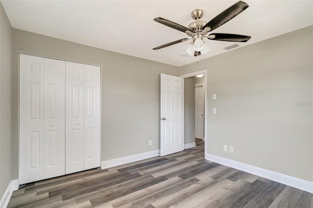 unfurnished bedroom featuring wood finished floors, a closet, baseboards, and a ceiling fan