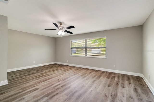 unfurnished room with wood finished floors, baseboards, and ceiling fan