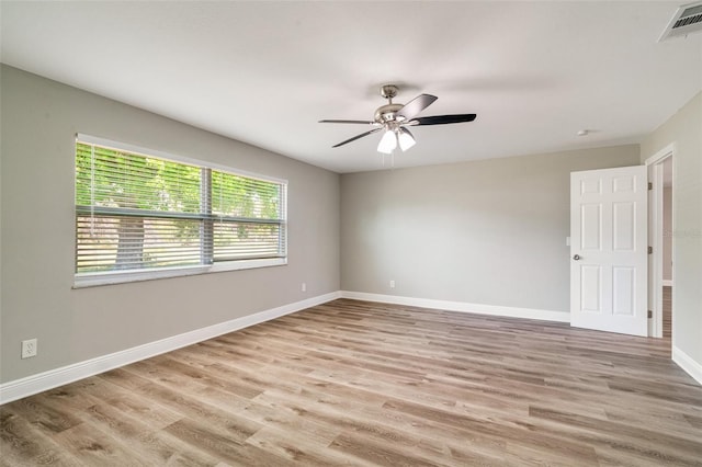 empty room with a ceiling fan, light wood finished floors, and baseboards