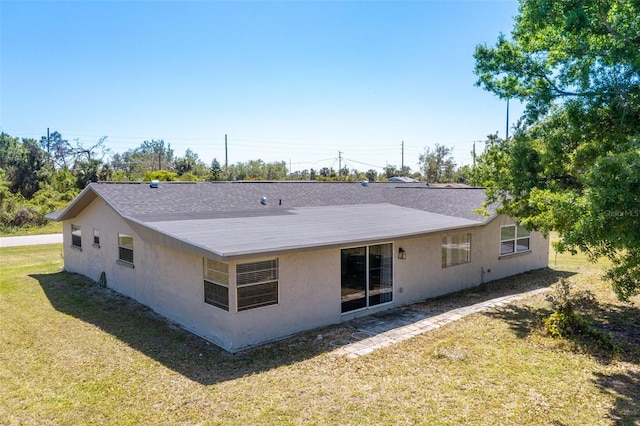 rear view of house featuring stucco siding and a lawn