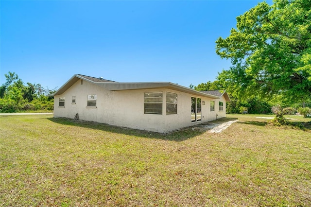 view of side of property with stucco siding and a lawn
