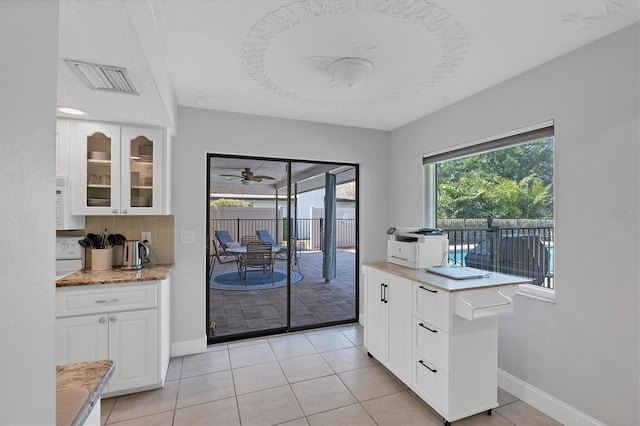4806 Huntleigh Dr, Sarasota, FL 34233 - kitchen featuring visible vents, baseboards, glass insert cabinets, light tile patterned floors, and white cabinetry