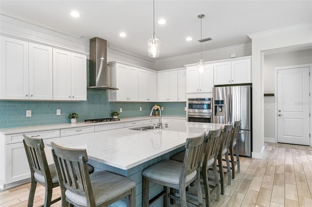 kitchen with tasteful backsplash, appliances with stainless steel finishes, wall chimney range hood, ornamental molding, and a sink