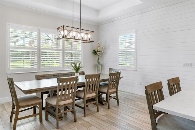 dining room with light wood finished floors, an inviting chandelier, and a raised ceiling