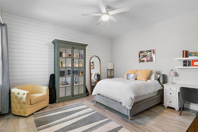 bedroom with wooden walls, a ceiling fan, light wood finished floors, and access to outside