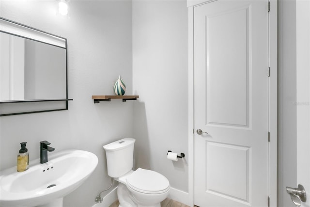 bathroom featuring toilet, a sink, and baseboards