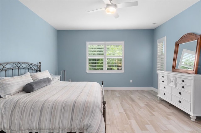 bedroom featuring ceiling fan, light wood-style flooring, and baseboards