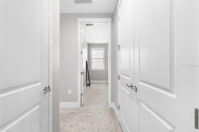 hall featuring light colored carpet, visible vents, and baseboards