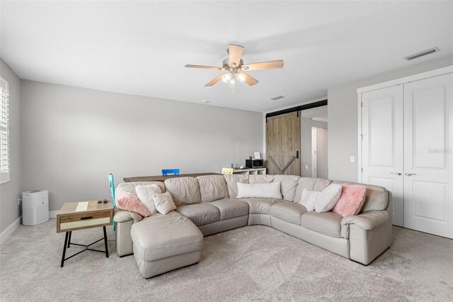 carpeted living area with visible vents, a ceiling fan, baseboards, and a barn door
