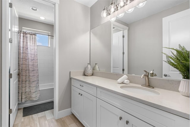 bathroom with baseboards, wood finished floors, shower / tub combo with curtain, and vanity