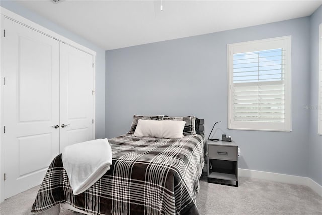 carpeted bedroom with a closet and baseboards