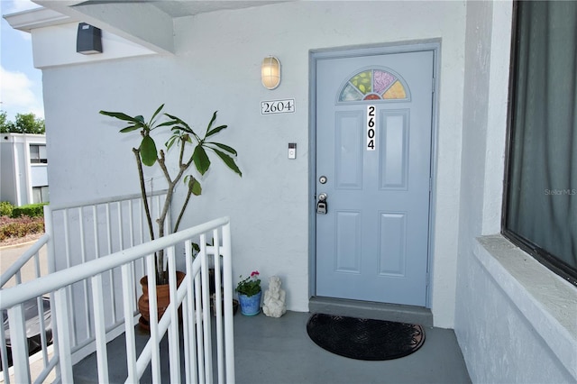 view of exterior entry featuring covered porch and stucco siding