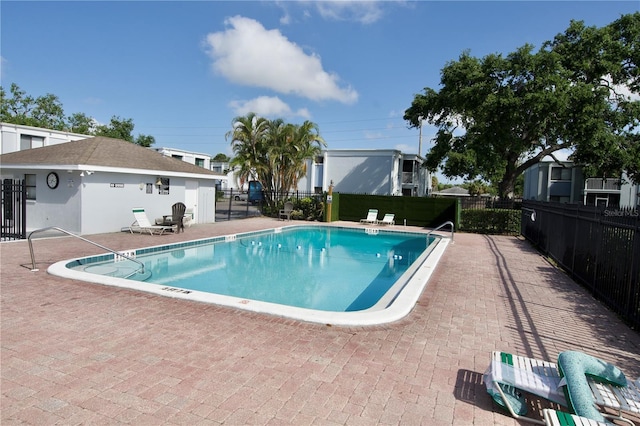 pool with a patio area and fence