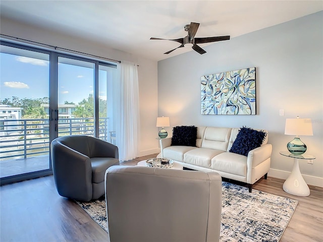 living area featuring wood finished floors, baseboards, and ceiling fan