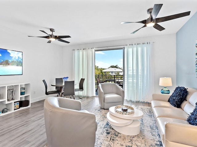 living room featuring baseboards, light wood-style flooring, and a ceiling fan