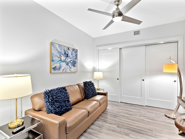 living room with visible vents, light wood-style flooring, and ceiling fan